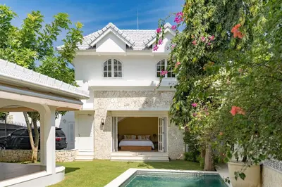 a white house with a bed and a swimming pool at The Heritage 4BR Villa Luxury Oasis in Canggu