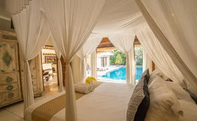 a bedroom with a canopy bed and a swimming pool at Villa Umah Maya in Seminyak