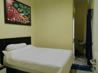a bedroom with a bed and a painting on the wall at Terace Campus A4 in Jimbaran