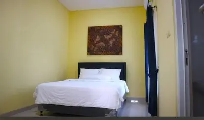 a bedroom with a bed with a painting on the wall at Terace Campus A4 in Jimbaran