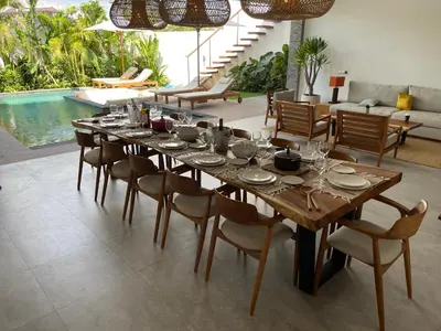 a dining room with a table and chairs and a pool at Lux 500sqm 5BR Villa, 400m to FINNS & Canggu Beach in Canggu