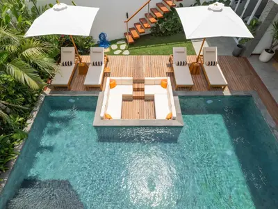 a pool with chairs and a table with umbrellas at Lux 500sqm 5BR Villa, 400m to FINNS & Canggu Beach in Canggu