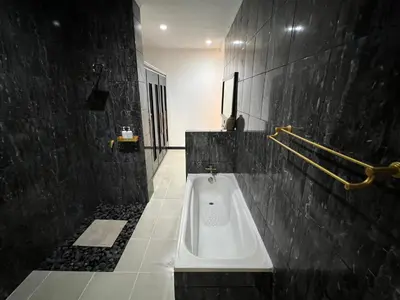 a bathroom with a white tub in a black wall at Villa Mawar Seminyak in Seminyak