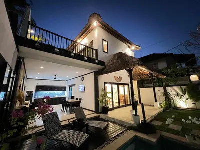a house with a patio with chairs and an umbrella at Villa Mawar Seminyak in Seminyak