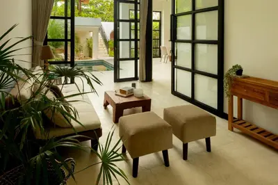 a living room with chairs and a table and a piano at Balidroomvilla Sanur Mangrove - Full Serviced - Beachside in Sanur