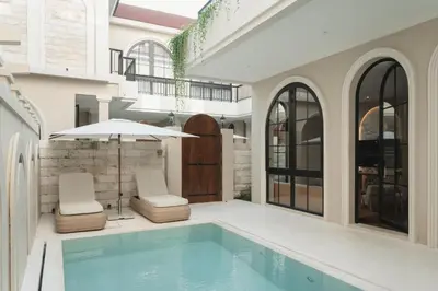 a swimming pool with two chairs and an umbrella at Hygge Hotel and Villas Seminyak in Seminyak