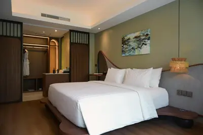 a bedroom with a large white bed and a bathroom at Hygge Hotel and Villas Seminyak in Seminyak
