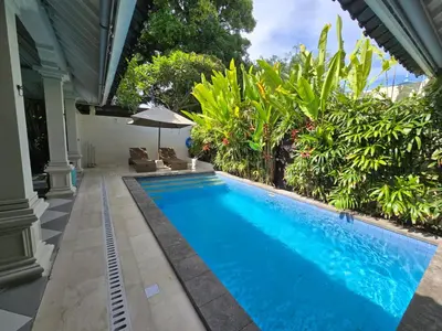 a swimming pool in front of a house at Villa Seni in Seminyak