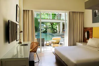 a hotel room with a bed and a view of a pool at Bali Paragon Resort Hotel in Jimbaran