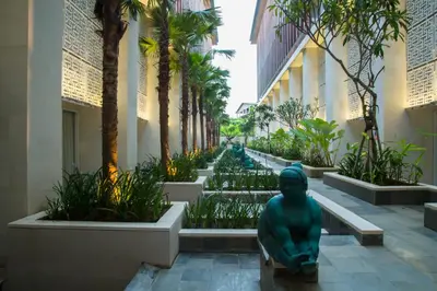 a statue in the middle of a courtyard with palm trees at Bali Paragon Resort Hotel in Jimbaran