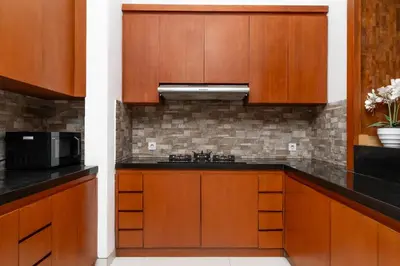 a kitchen with wooden cabinets and a microwave at Bale Gede Luxury Villas by Moria in Canggu