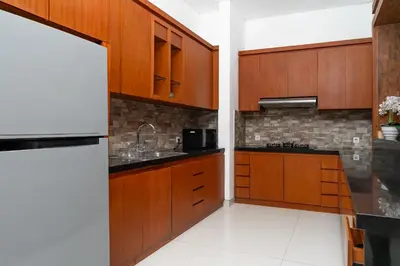 a kitchen with wooden cabinets and a sink at Bale Gede Luxury Villas by Moria in Canggu