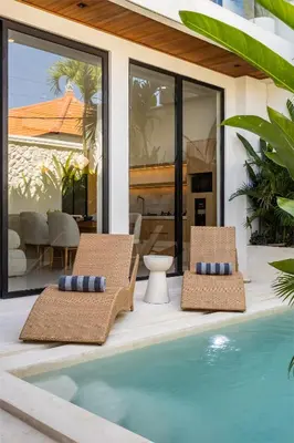 two chairs and a swimming pool in front of a house at Villa Oasia 2 Seminyak in Seminyak
