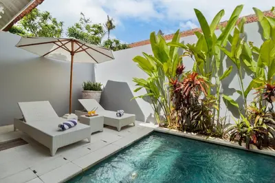 a patio with a pool and chairs and an umbrella at Perfect for Couples and Solo Travellers in Seminyak