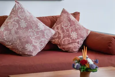 a couch with two pillows and a table with flowers at Perfect for Couples and Solo Travellers in Seminyak