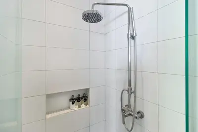 a shower in a bathroom with white tiles at Perfect for Couples and Solo Travellers in Seminyak