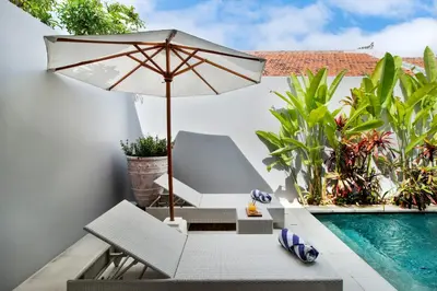 an umbrella and a chair next to a swimming pool at Perfect for Couples and Solo Travellers in Seminyak