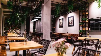 a restaurant with wooden tables and chairs and plants at Nature's Immersion Room at Anwa Bali Boutique Resort in Canggu