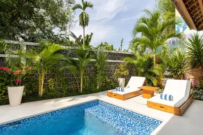 a backyard pool with two chairs and a swimming pool at Stunning Garden Room with Private Pool at Anwa Bali in Canggu