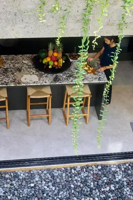a woman sitting at a table with a bowl of fruit at The Riverfront 5BR Luxury Villa Near the Beach in Canggu
