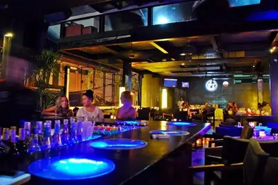 a group of people sitting at a bar in a restaurant at SG Hotel - 2 Minutes to the Beach By Micky Studio 1 in Legian