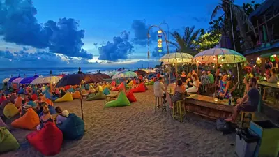 a group of people sitting on a beach with umbrellas at SG Hotel - 2 Minutes to the Beach By Micky Studio 1 in Legian