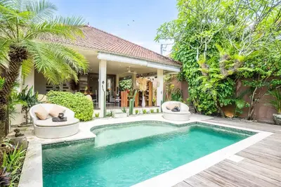 a swimming pool with two chairs next to a house at Villa CC- Cosy 2bdrs villa - enclosed and open living area in Seminyak