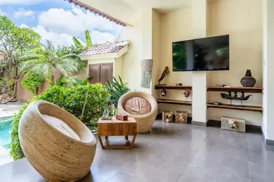 a living room with a tv and a chair and a table at Villa CC- Cosy 2bdrs villa - enclosed and open living area in Seminyak