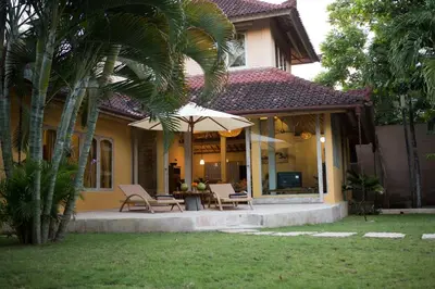 a house with a patio with chairs and an umbrella at Two bedroom Villa in a beautyful tropical garden in Seminyak