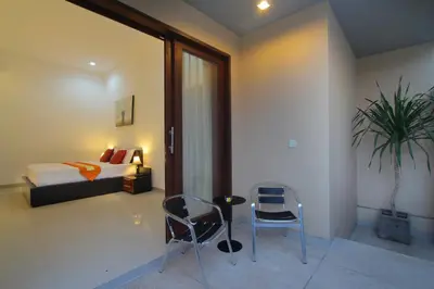 a bedroom with two chairs and a bed and a plant at Lotus Tirta Seminyak in Seminyak