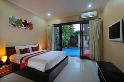 a bedroom with a bed and a sliding glass door at Lotus Tirta Seminyak in Seminyak