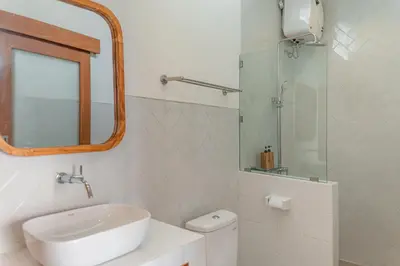a white bathroom with a sink and a mirror at Comoda Seminyak in Seminyak