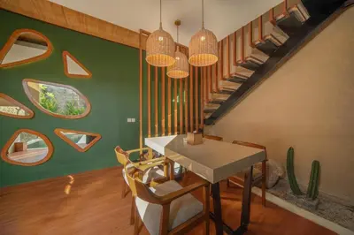 a dining room with a table and a staircase at Ini Vie Villa Seminyak by Ini Vie Hospitality in Legian