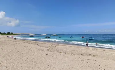 a group of people walking on a beach at ABI Hotel - 1 minute to the Beach and 1 second to the Mall in Ngurah Rai International Airport