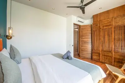 a bedroom with a white bed and wooden cabinets at Chic Modern 3BR Villa, Enclosed Living Room in Canggu