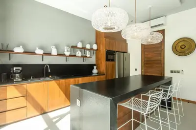 a kitchen with a black counter top and wooden cabinets at Chic Modern 3BR Villa, Enclosed Living Room in Canggu