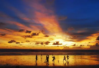 a group of people running on the beach at sunset at SC Hotel - 1 Minute to the Beach By Micky Studio in Badung