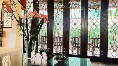 a vase with flowers on a glass table with a window at Cempaka Villa in Pesanggaran