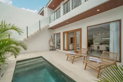 a house with a swimming pool and two chairs at Cute 2 Bedrooms Villa in Canggu in Canggu