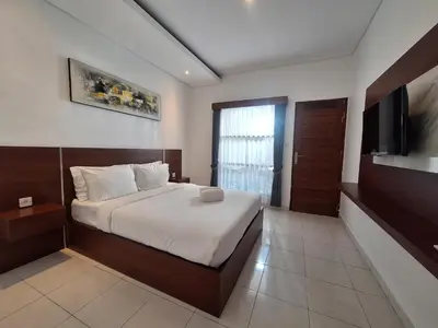 a bedroom with a bed and a flat screen tv at Saphala Suites Seminyak in Seminyak