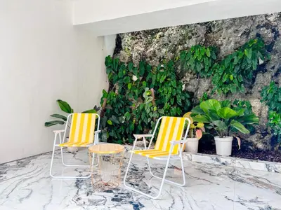 two chairs and a table in front of a stone wall at Budayana Villa in Jimbaran