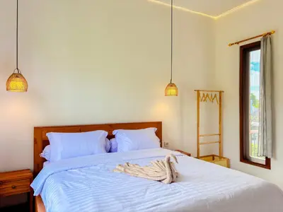 a bedroom with a bed with white sheets and a window at Budayana Villa in Jimbaran