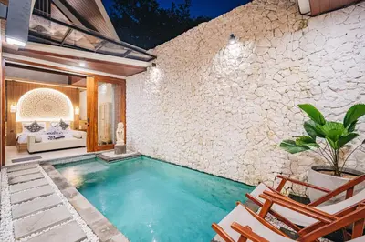an indoor swimming pool with chairs and a house at iRini Villas in Nusa Dua