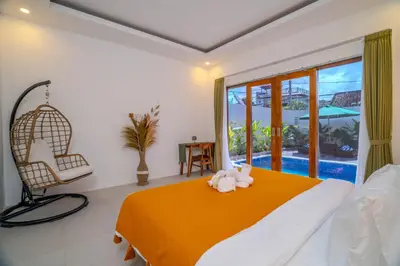 a bedroom with a bed and a chair and a window at Villa Radha Seminyak in Seminyak