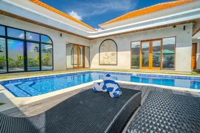 a swimming pool in a house with a teddy bear sitting on a bench in at Villa Radha Seminyak in Seminyak