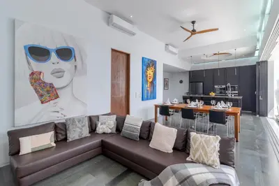 a living room with a brown couch and a kitchen at Stylish 3BR Villa with Swim-Up Bar in Seminyak in Seminyak