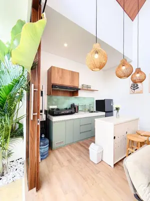 an open kitchen with green and white cabinets and pendant lights at Villa De Tutti - 2BR Pool Villa Near Seminyak in Seminyak