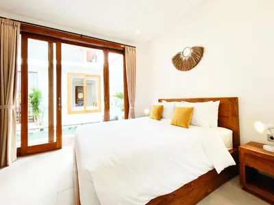 a white bedroom with a large bed and a window at Villa De Tutti - 2BR Pool Villa Near Seminyak in Seminyak