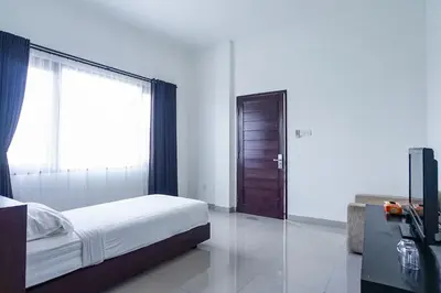 a bedroom with a bed and a large window at Prima Inn in Kuta
