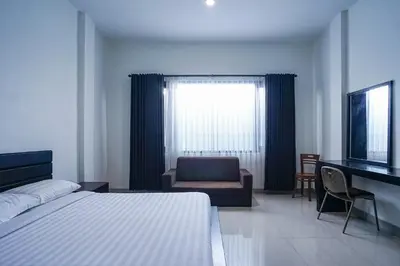 a bedroom with a bed and a desk and a television at Prima Inn in Kuta